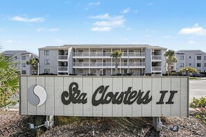 Indicador de Sea Clusters II, un edifici de diverses plantes amb balcons i un cel clar al fons.