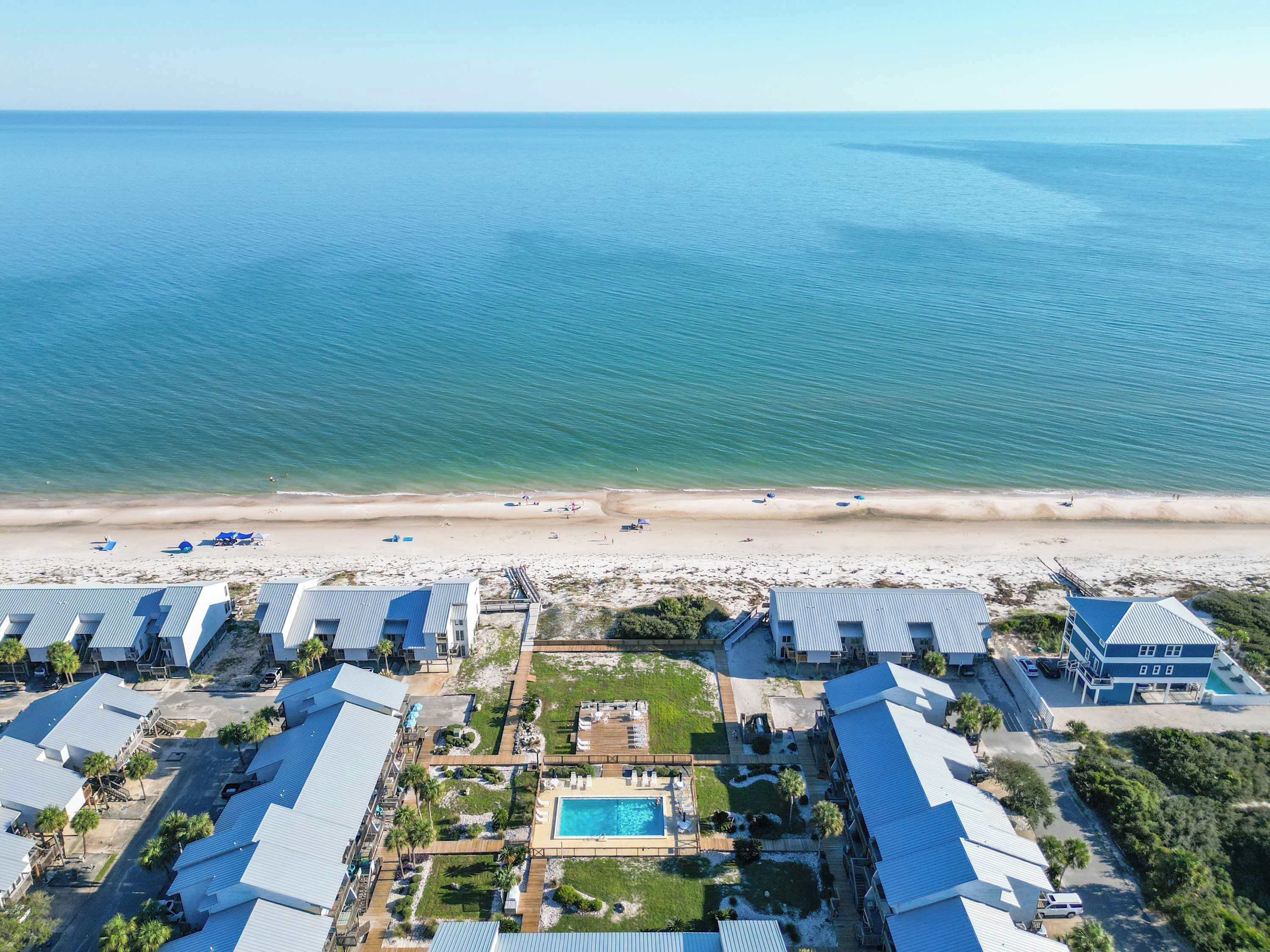 A resort with multiple buildings, a swimming pool, and a beach.
