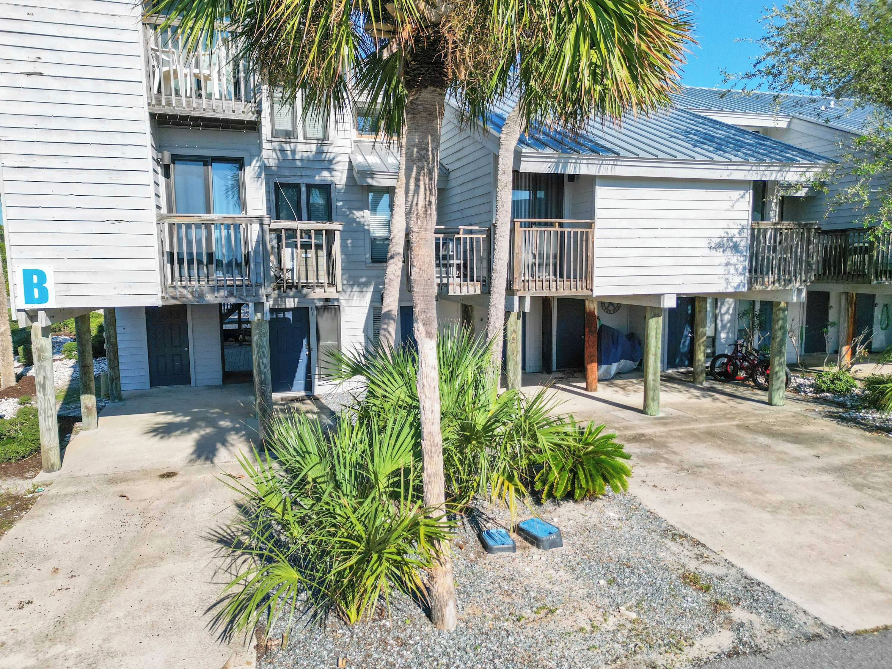 A beachfront property with multiple balconies, a palm tree, and a motorcycle.