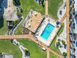 An aerial view of a resort with a swimming pool, wooden deck, and lounge area.