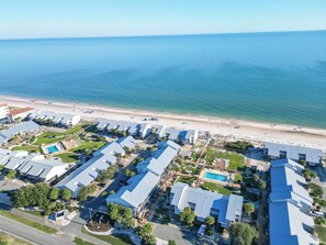 Un complejo turístico frente al mar, con varias construcciones, piscina y playa.