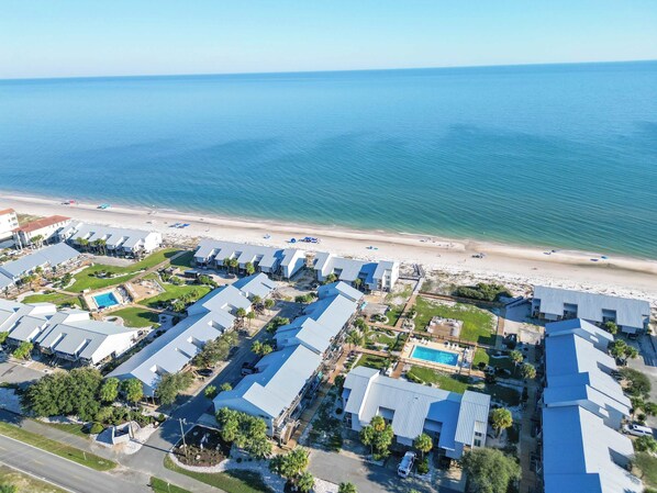 A coastal resort with multiple buildings, a pool, and a beach.