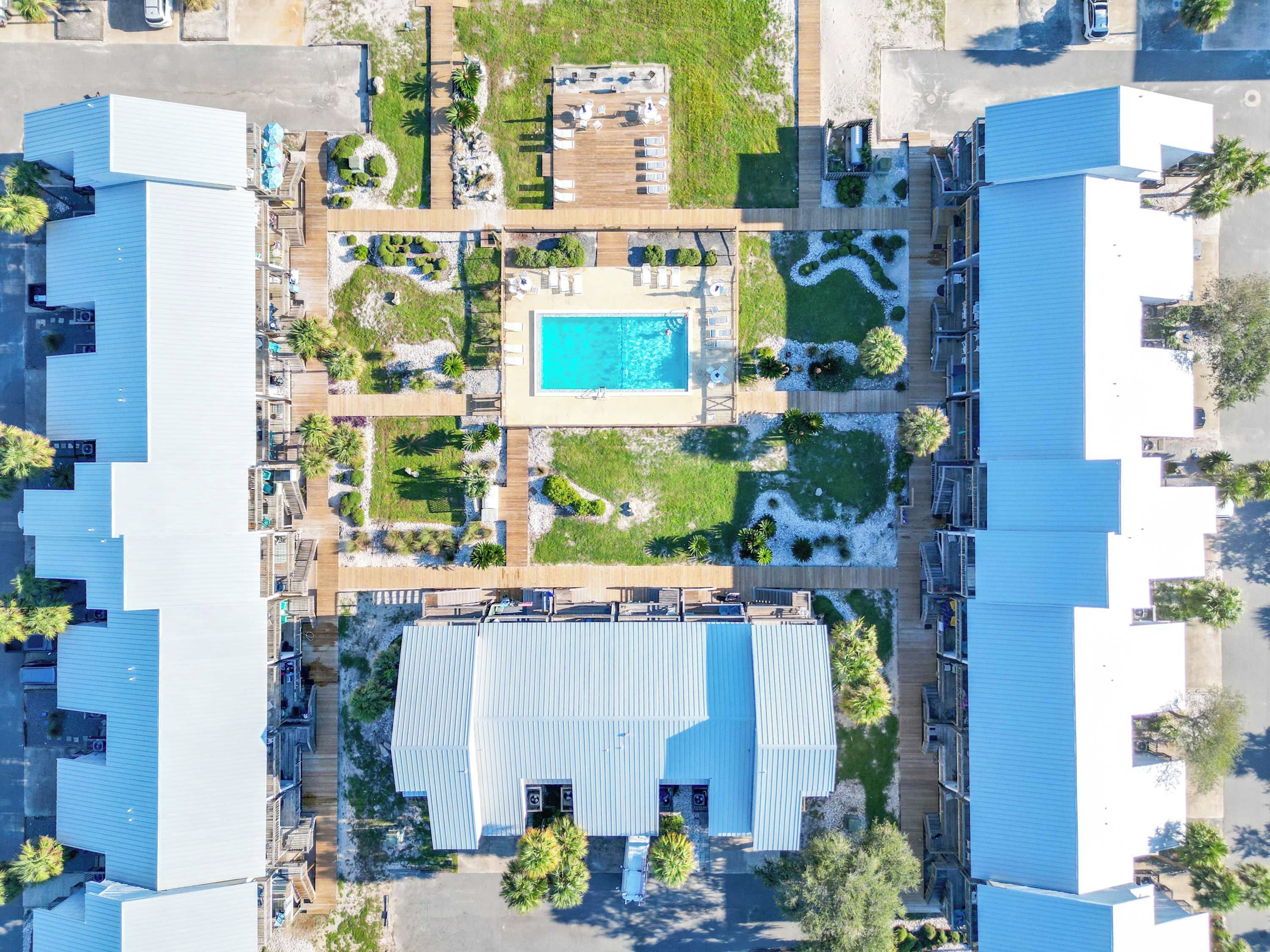 A large building with a central swimming pool, surrounded by landscaped areas and multiple decks.