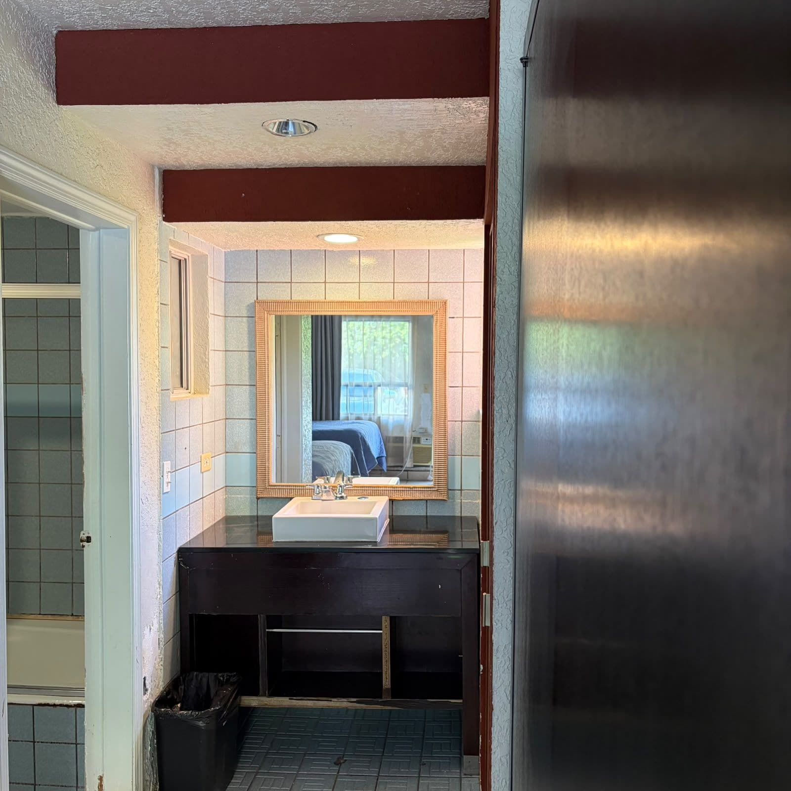 A bathroom with a sink, mirror, and a shower area.