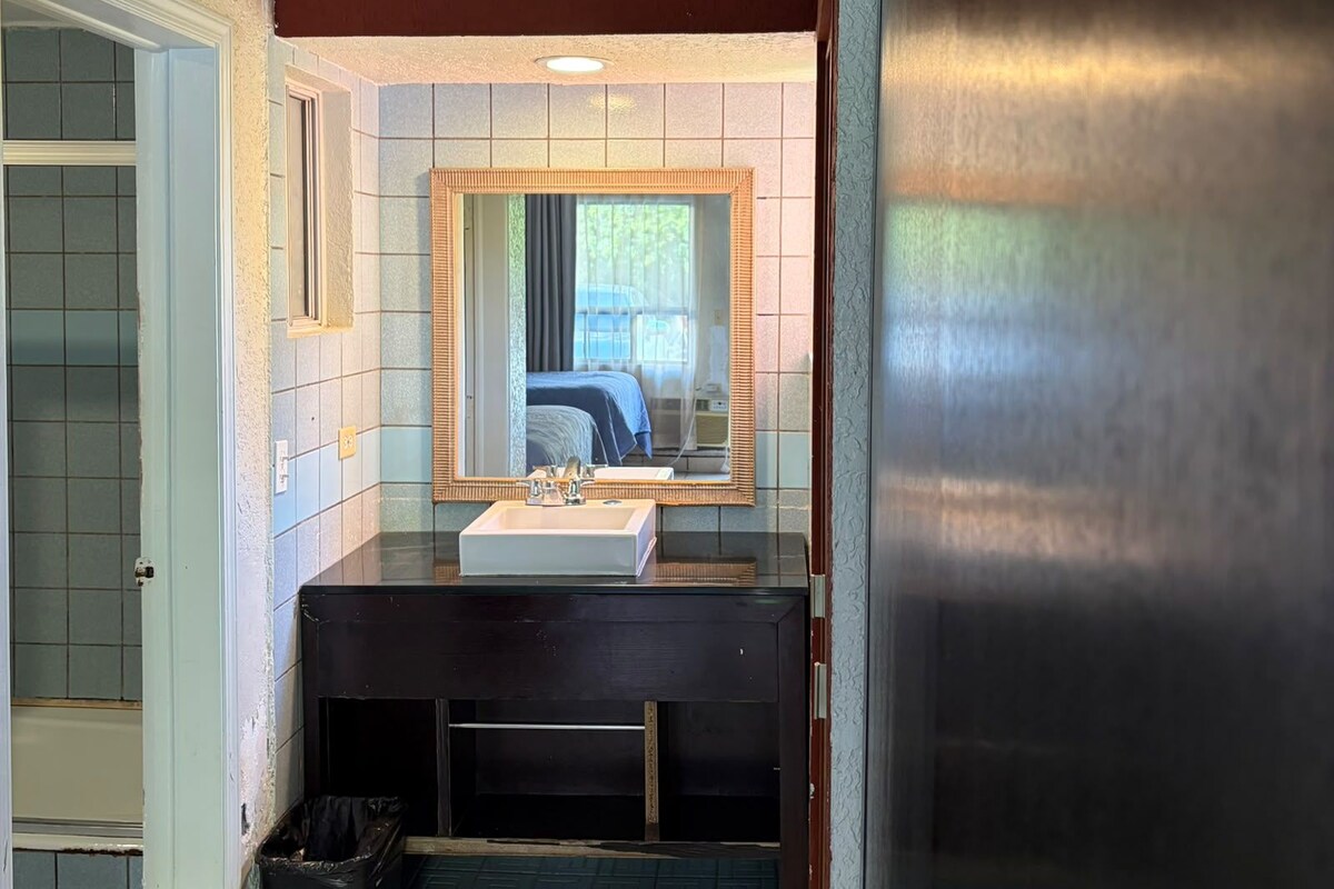 Baño con lavamanos, espejo y zona de ducha.
