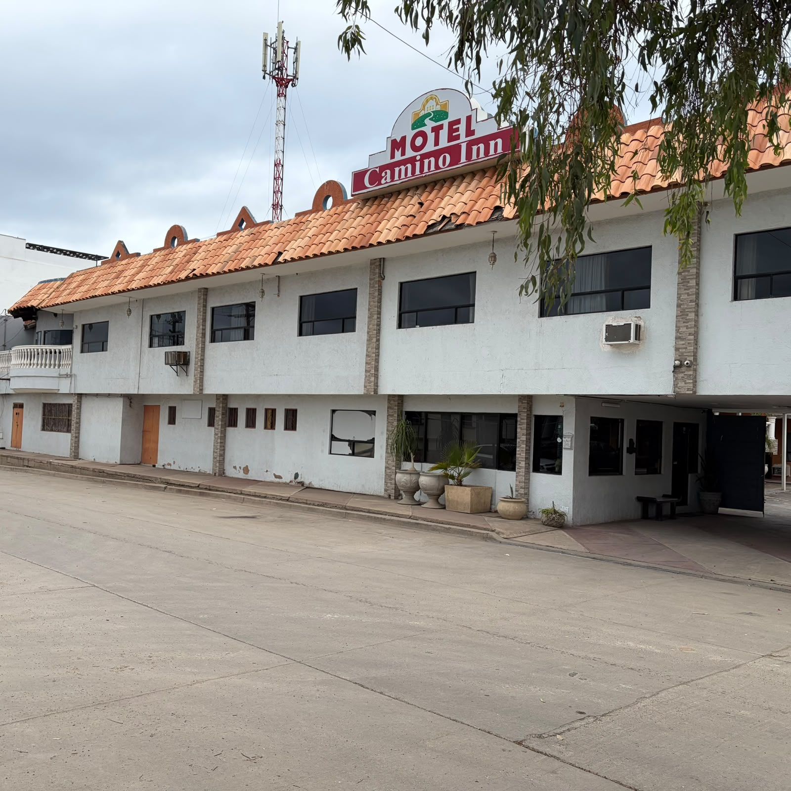A two-story motel with a tiled roof, multiple windows, and outdoor seating area.
