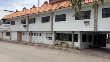 A two-story motel with a tiled roof, multiple windows, and outdoor seating area.