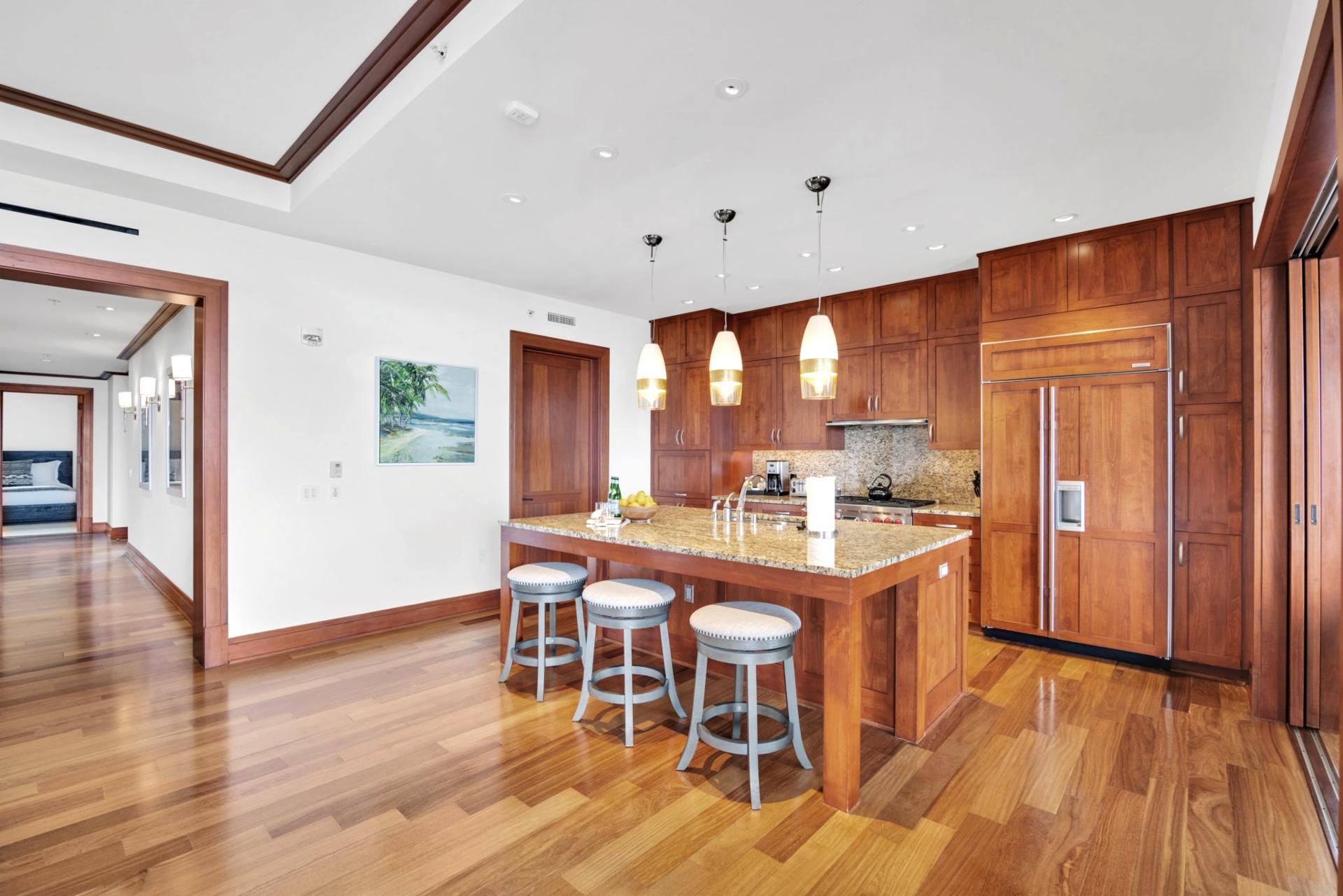 A modern kitchen with wooden cabinets, a granite countertop, and three bar stools.