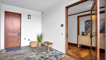 A stone-floored entrance with a wooden door, a small table, and a welcome mat.