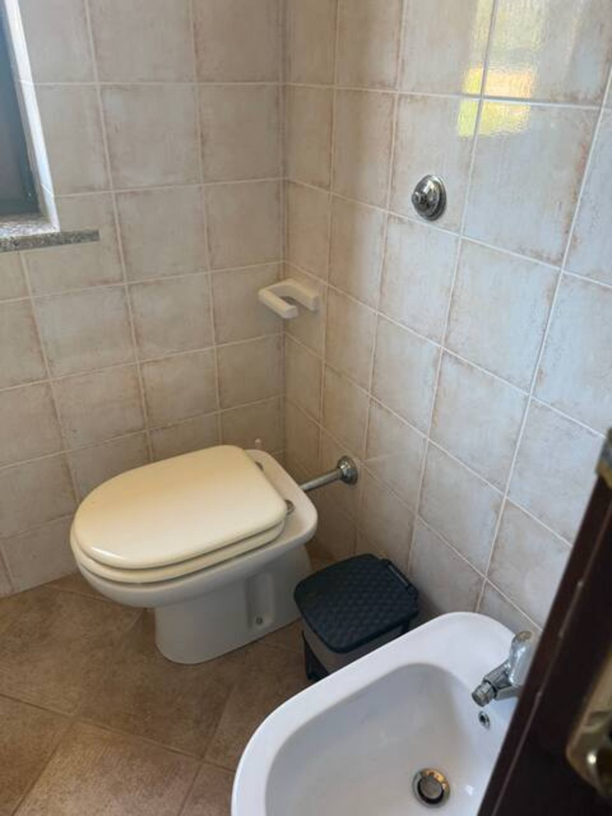Ein kleines Badezimmer mit Toilette, Waschbecken und Fliesen.