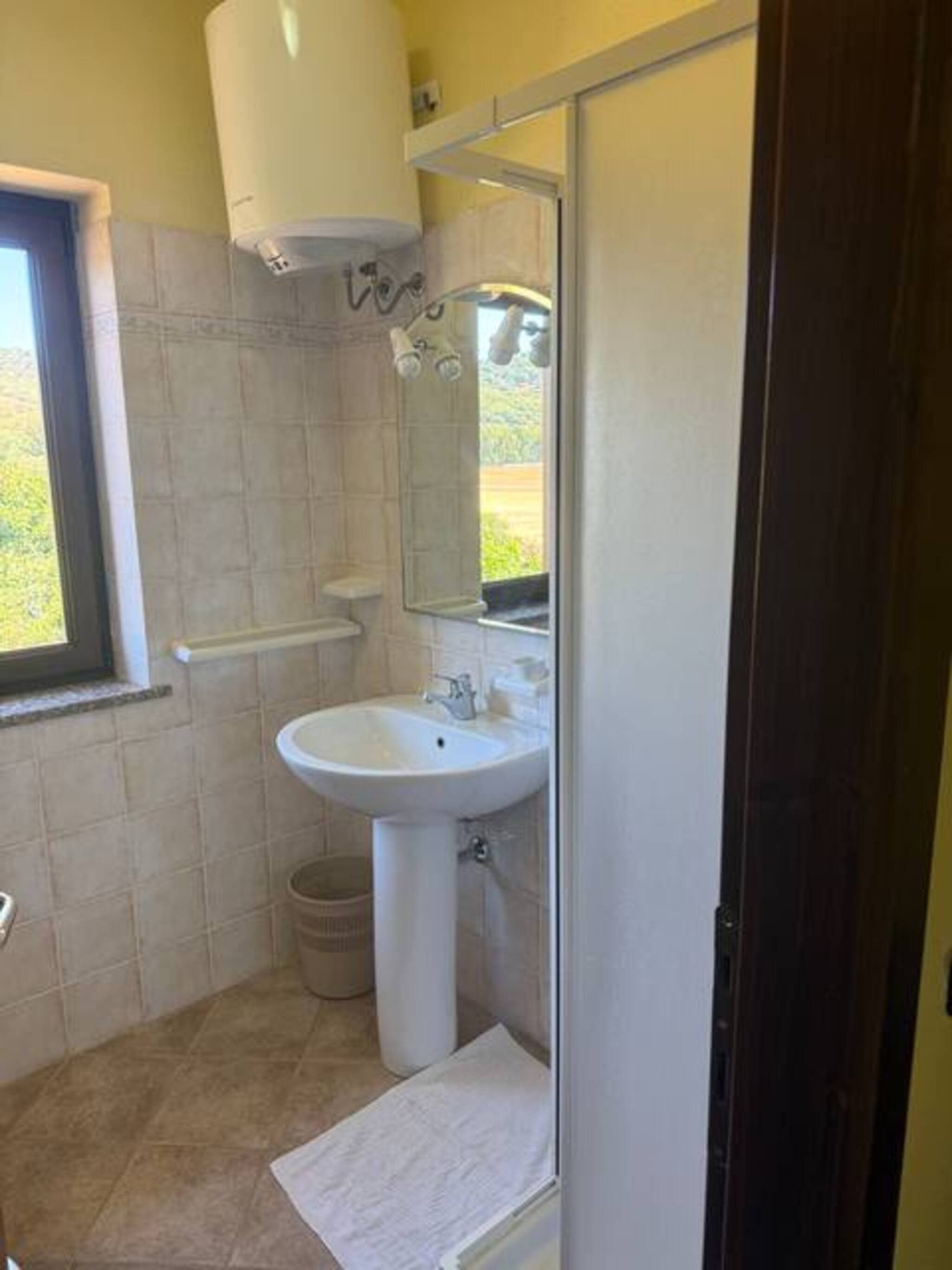 A bathroom with a sink, mirror, and window.