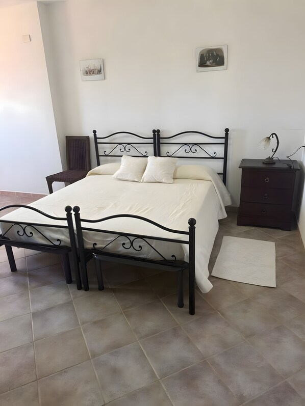 A bedroom with a bed, a nightstand, a chair, and a rug. - Room 'Tripla Standard 2' with Shared Terrace, Wi-Fi and Air Conditioning (Nulvi)