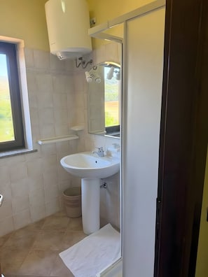 A bathroom with a white sink, a mirror, and a shower area. - Room 'Camera Tripla Standard 3' with Shared Terrace, Wi-Fi and Air Conditioning (Nulvi)