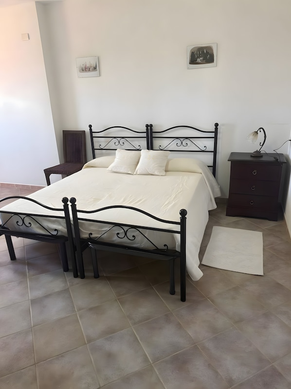 A bedroom with a bed, a nightstand, a chair, and a rug. - Room 'Tripla Standard 4' with Shared Terrace, Wi-Fi and Air Conditioning (Nulvi)