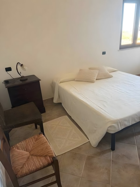 Een slaapkamer met een bed, bureau, stoel en raam.