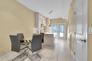 A modern kitchen with a dining area, featuring a central island, built-in cabinets, and a view through the glass door. - B243- Cozy 2-bedroom townhome in wonderful Harvie Heights with AC (Harvie Heights)