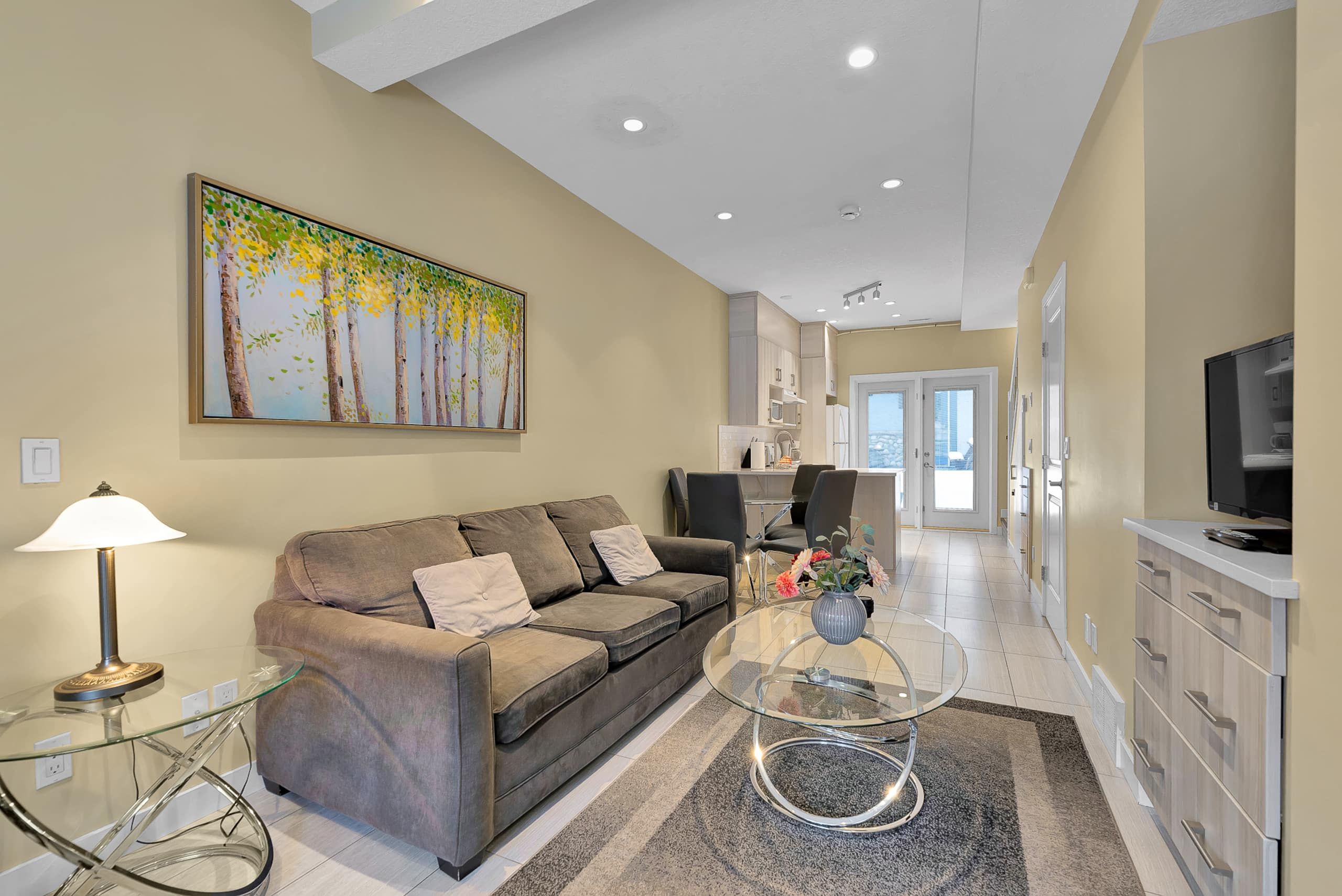 A modern living room with a sofa, a coffee table, and a painting on the wall.