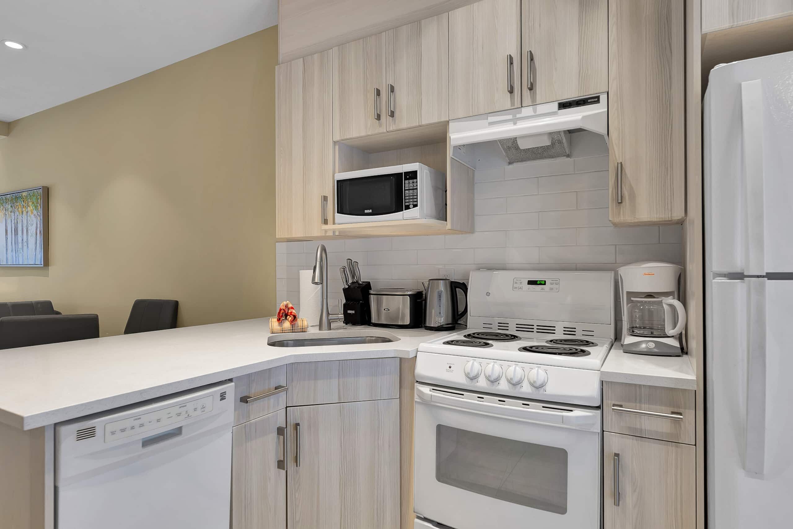 A modern kitchen with a dishwasher, stove, microwave, and coffee maker.