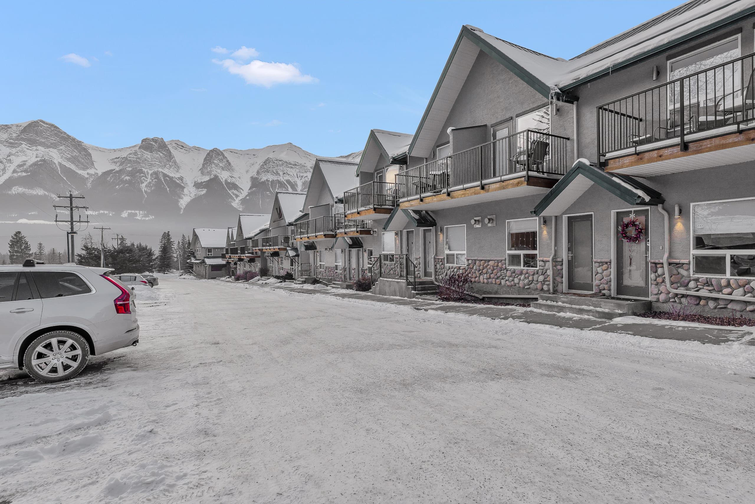 A residential street with houses featuring balconies and a mountainous backdrop.