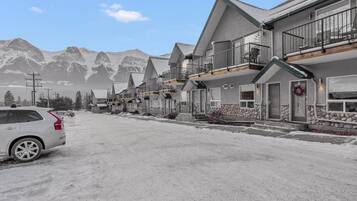 A residential street with houses featuring balconies and a mountainous backdrop.