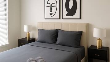 Een netjes opgemaakt bed met twee kussens, een paar opgerolde handdoeken en twee nachtkastjes met lampen.