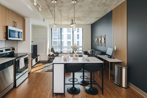 Een moderne keuken met een centraal eiland, een ingebouwde magnetron en roestvrijstalen apparatuur.