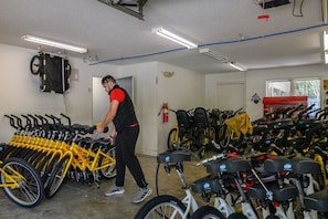 Une station de location de vélos où l’on trouve plusieurs vélos, et une personne qui s’occupe de les organiser.