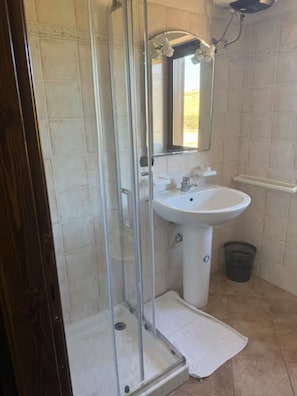 Un bagno con box doccia in vetro, lavandino e specchio.