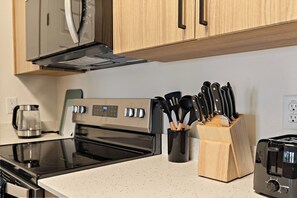 Une cuisine équipée d’une cuisinière en acier inoxydable, d’une machine à café et d’un bloc à couteaux.