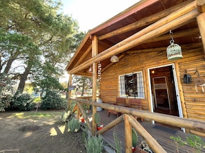 A wooden cabin with a porch, a window, and a door. - New Listing (Ostende)