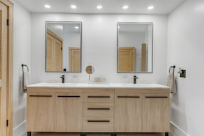 Une salle de bain moderne avec deux lavabos, des meubles en bois et des miroirs.