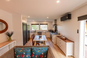 Una cocina moderna con comedor, suelo de madera y un amplio ventanal que proporciona luz natural.