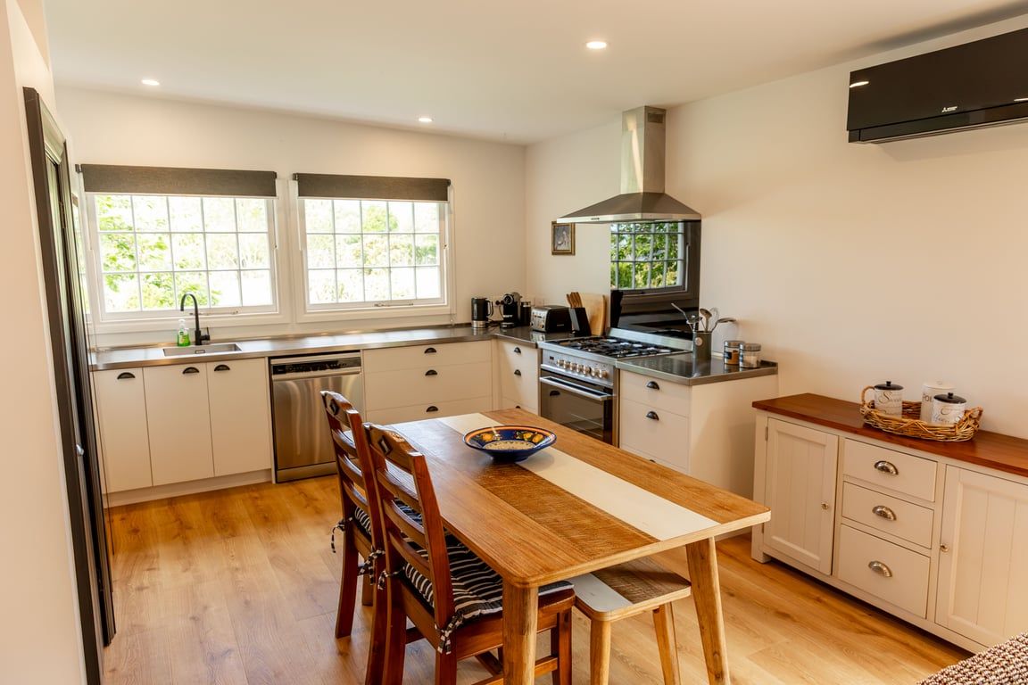 A kitchen with white cabinets, a wooden dining table, and a stove.