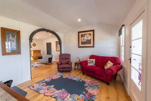 Uma sala de estar com um sofá vermelho, uma poltrona de couro e um tapete estampado com flores.