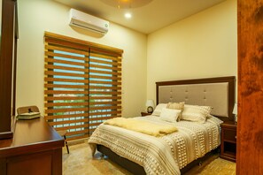 A bedroom with a bed, nightstands, a desk, and a window with blinds. - Elegant 2BR Condo with Pool in Vibrant La Paz (lA paZ)