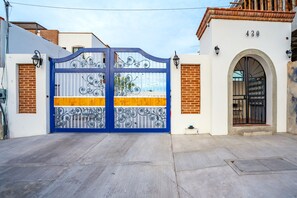 A gated entrance with a blue and yellow gate, a brick wall, and a number '430' on a building. - Elegant 2BR Condo with Pool in Vibrant La Paz (lA paZ)