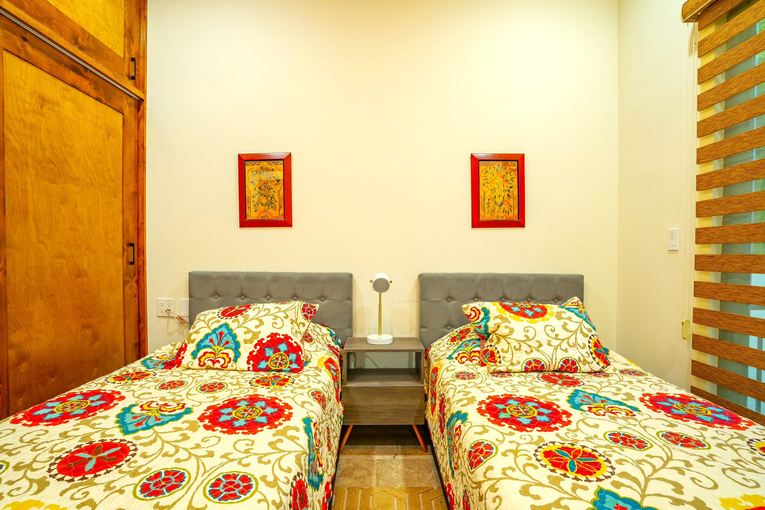 A double room with two beds, a wooden wardrobe, and a window with blinds.