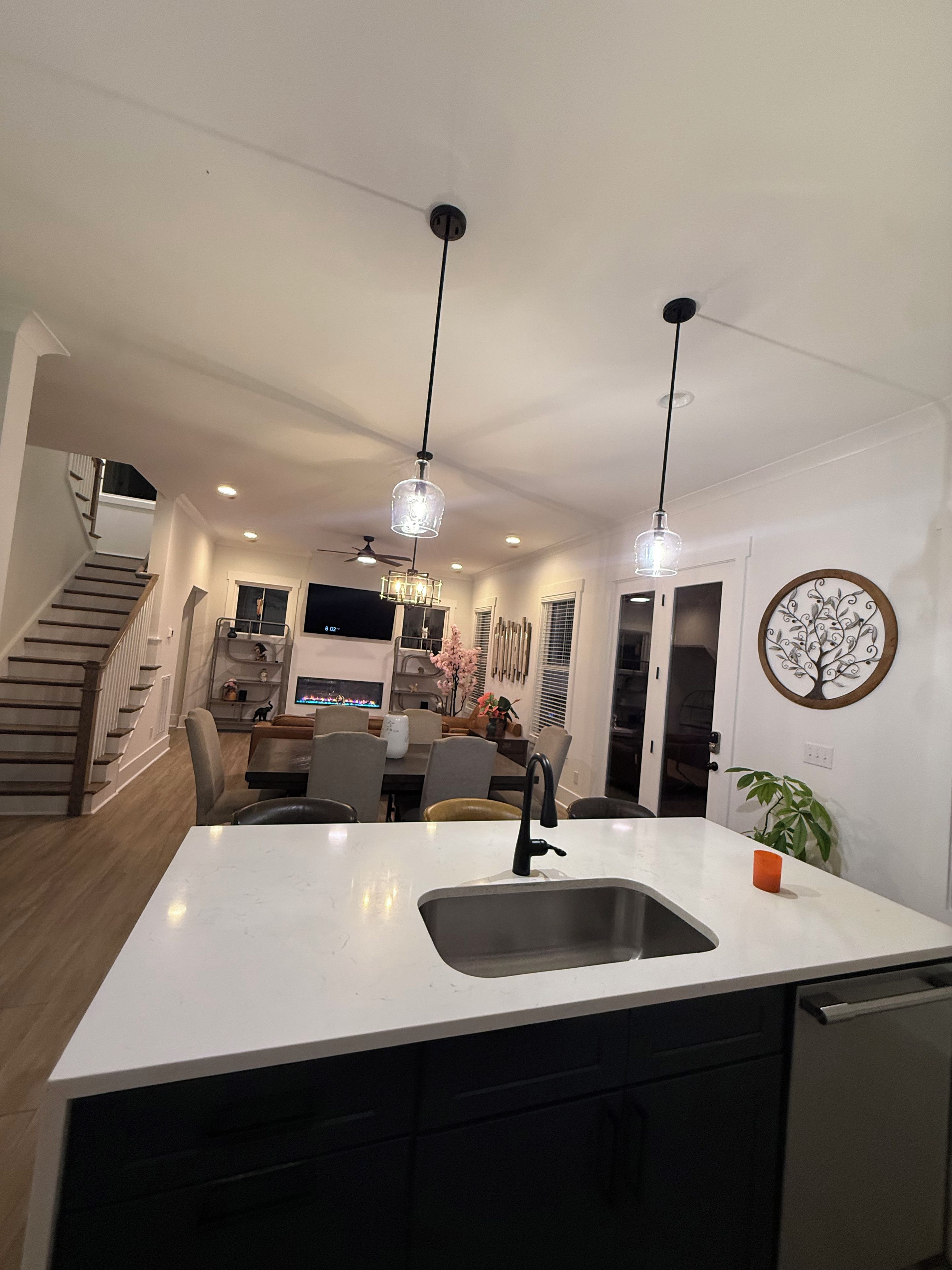 Une cuisine moderne dotée d’un îlot central, de luminaires suspendus et d’un escalier menant à un niveau supérieur.