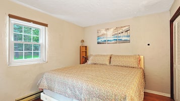 Une chambre à coucher avec un lit, une fenêtre, une étagère fixée au mur et un tableau.