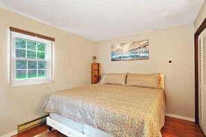 Une chambre à coucher avec un lit, une fenêtre, une étagère fixée au mur et un tableau.