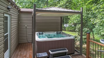 A hot tub on a wooden deck with a pergola overhead.