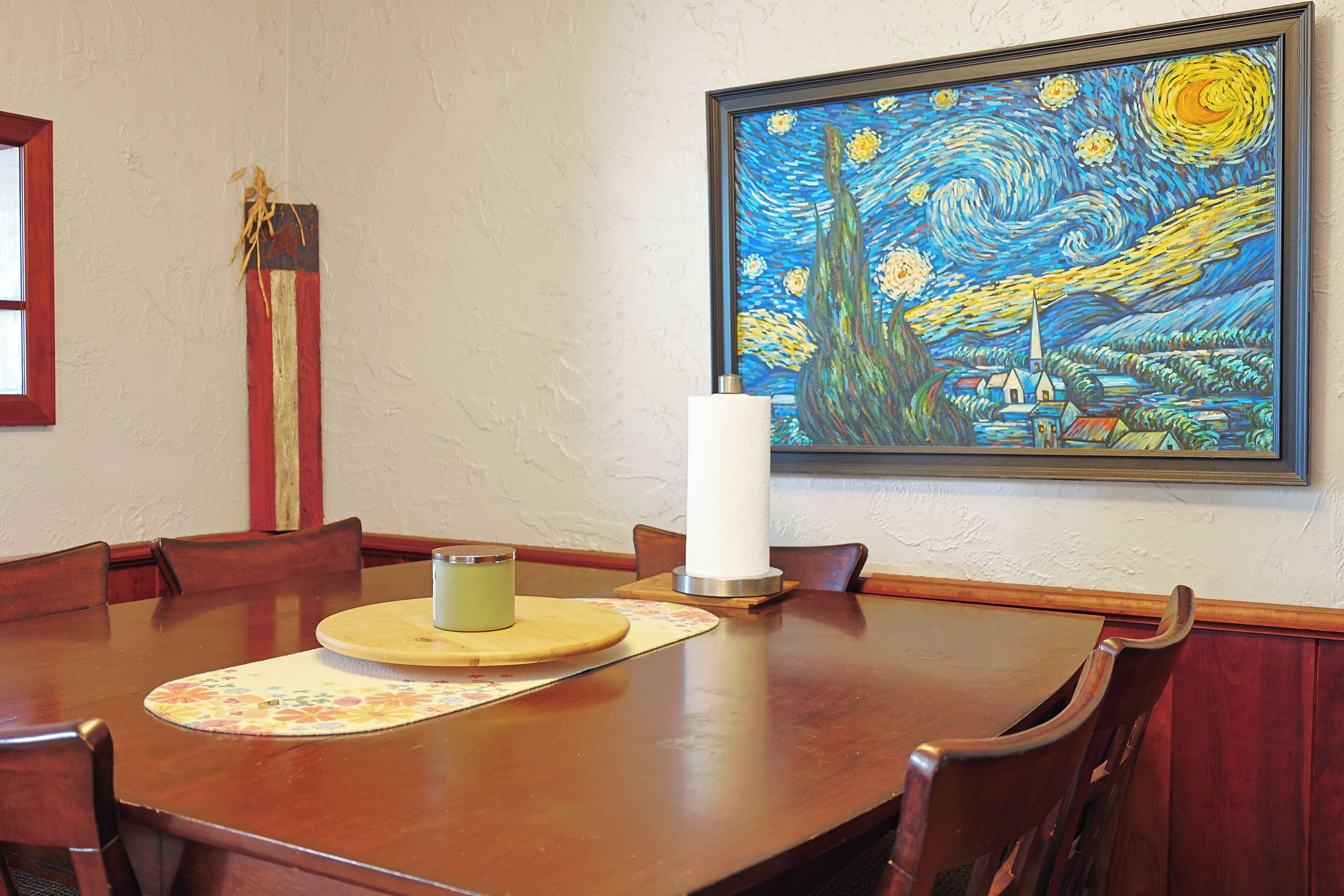 Une table à manger avec des chaises, une bougie et un tableau accroché au mur.