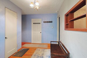Un couloir avec une porte blanche, un banc, un porte-manteau et un panneau indiquant : « Restons à l’intérieur ».