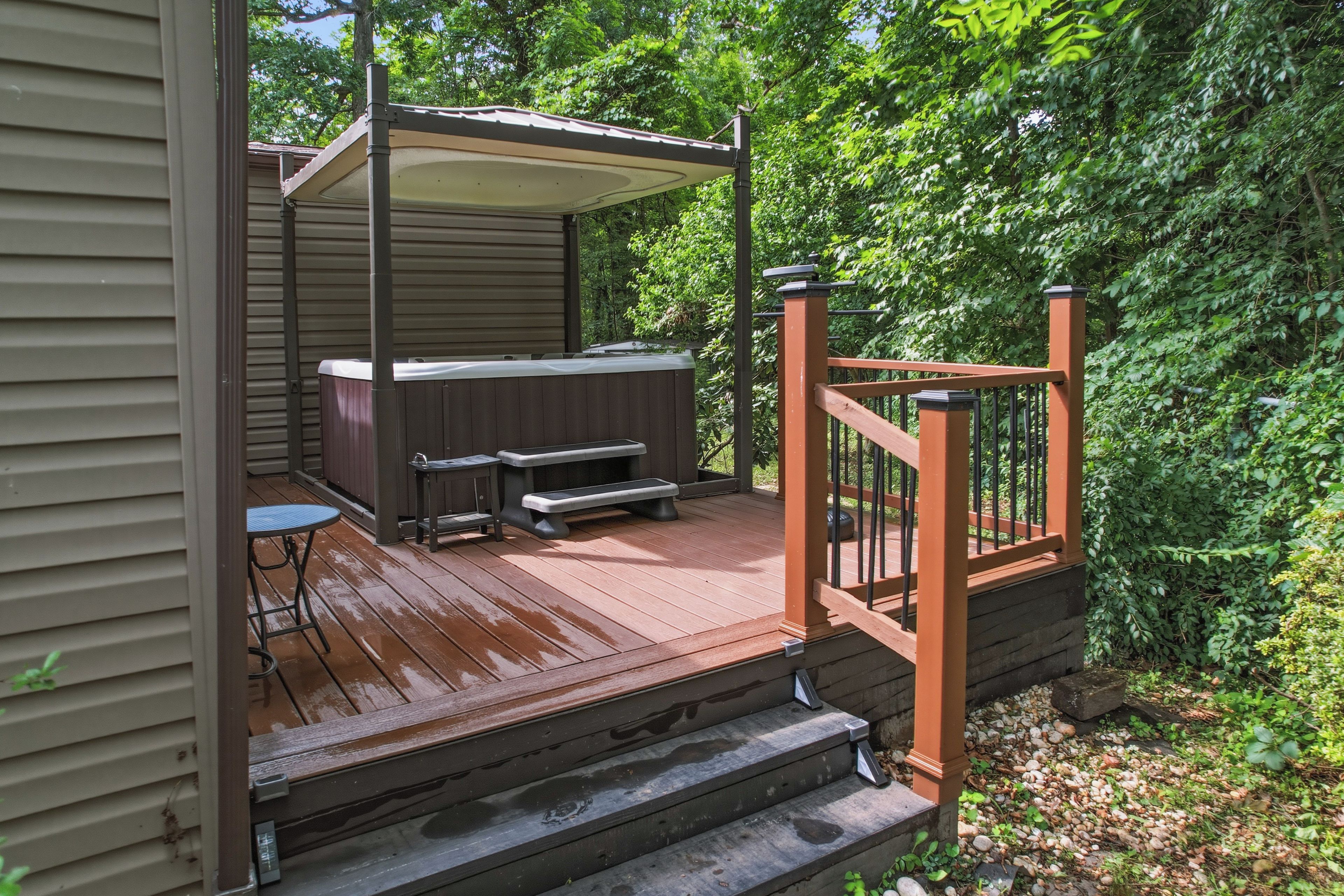 A wooden deck with a hot tub, a table, and benches.