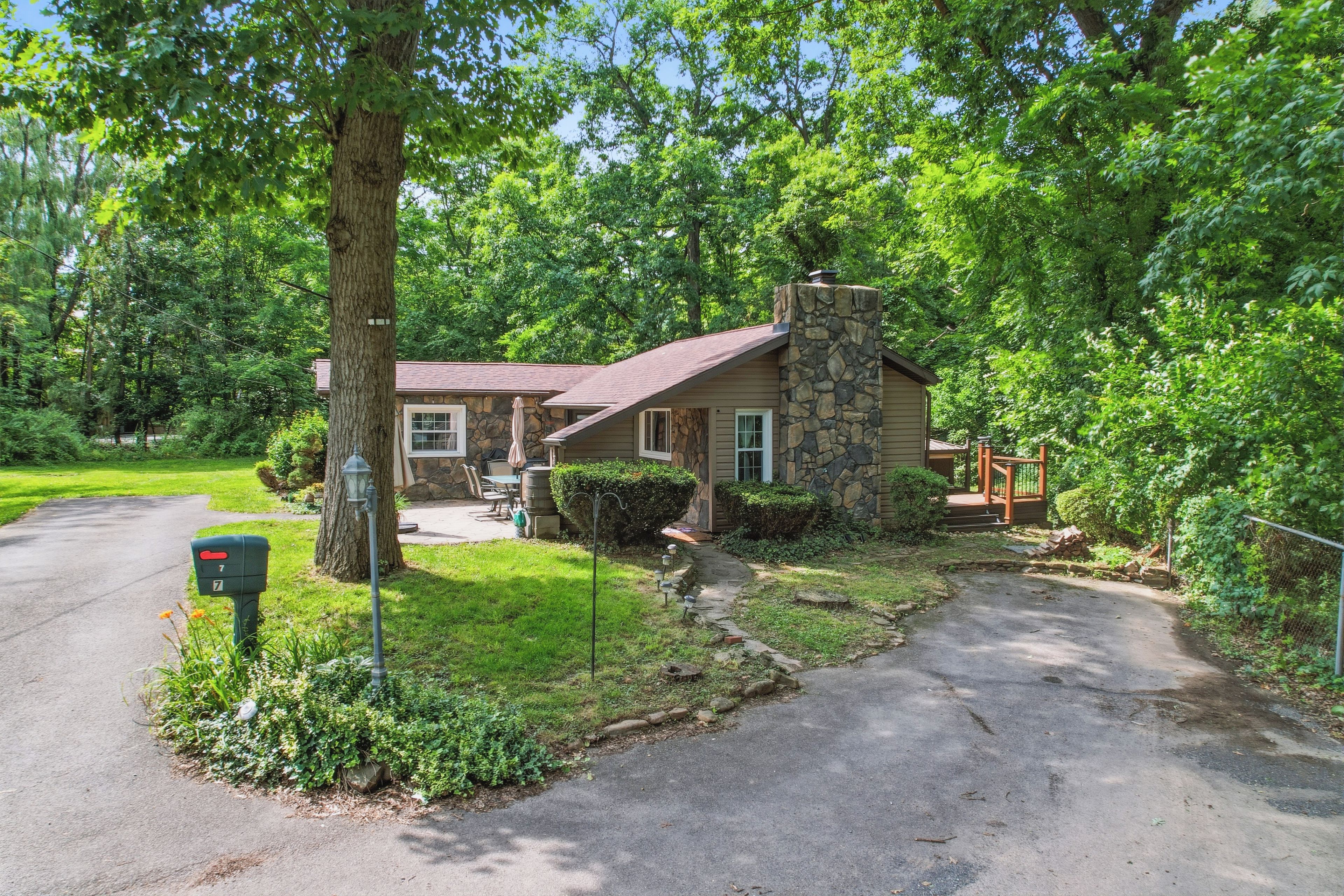 A two-story house with a stone chimney, a front porch, and a mailbox.