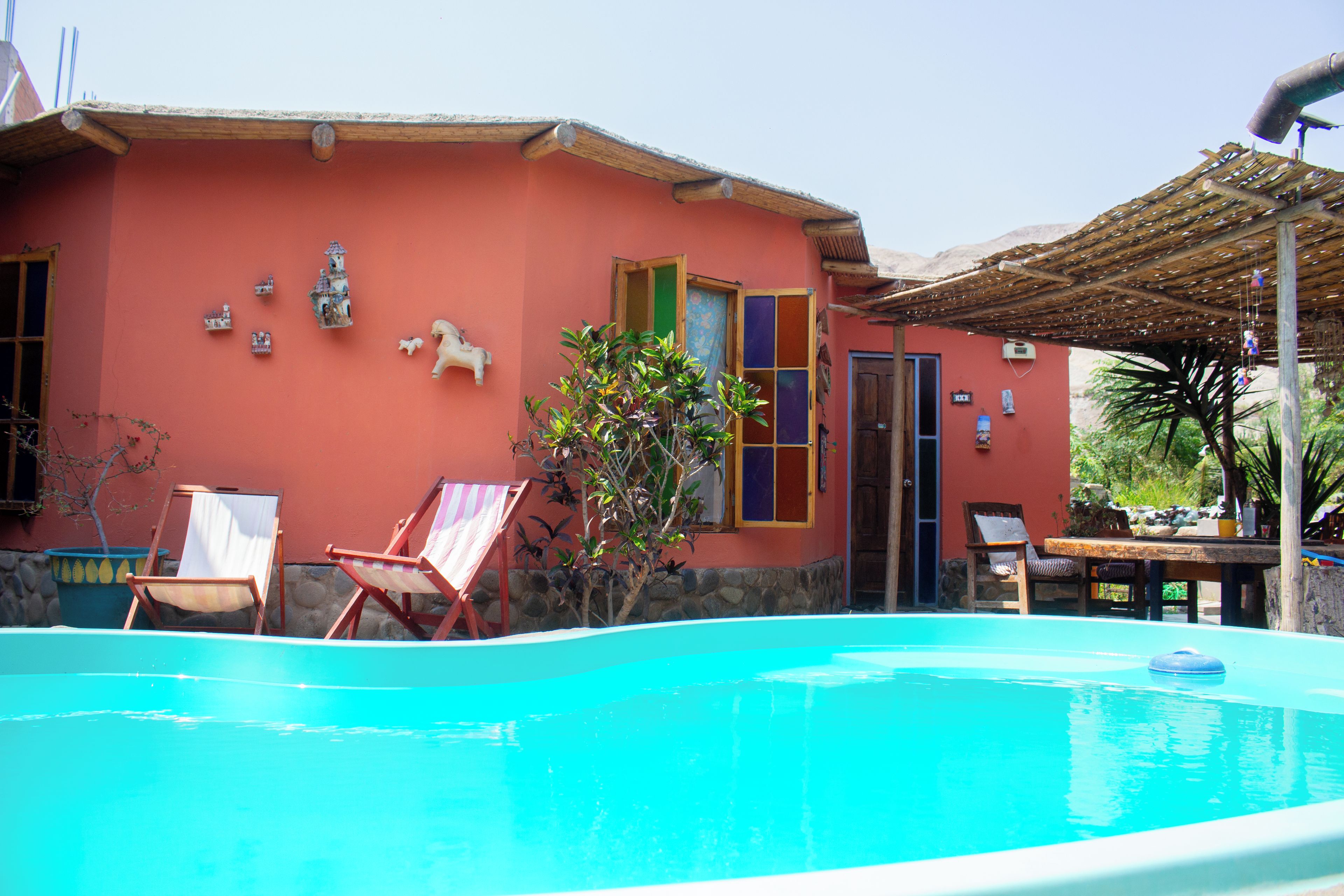 Una piscina con sillones de descanso y un pequeño jardín.