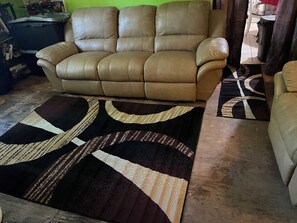 Ein beiges Ledersofa mit einem geometrisch gemusterten Teppich davor.