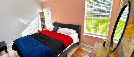 A bedroom with a bed, bedside table, and a window with blinds.