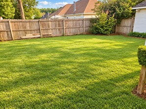 A well-maintained backyard with a wooden fence, a lawn, and a house in the background. - 3 King Beds • Fenced Yard • Pet-Friendly • Guest Favorit • Great location (Pooler)