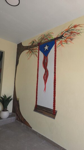 Un mur orné d’une décoration murale représentant une branche d’arbre, un drapeau et des glands rouges.
